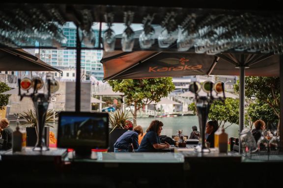 Customers seated at outside tables at Karaka Cafe at Te Wharewaka o Pōneke.