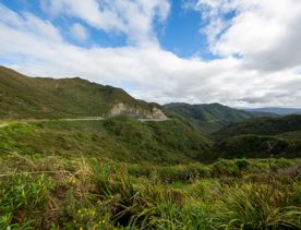 The screen location of Remutaka Summit, wit views of surrounding peaks, lush green bush and steep roads cut into the sides of the mountains.