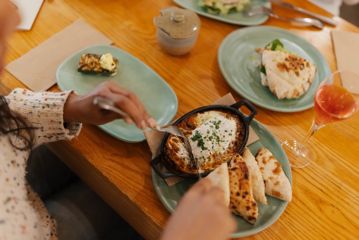 A person cuts into a shakshuka with a knife and fork.