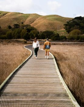 Two people walk along the boardwalk at Te Ara Piko.
