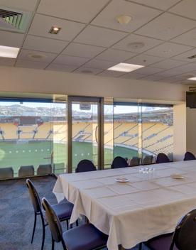 Table with 12 chairs around it in the Hnry Stadium Function centre box. In the background you can see the field and stands.