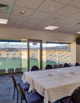 Table with 12 chairs around it in the Hnry Stadium Function centre box. In the background you can see the field and stands.