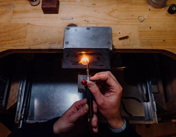 Hands brazing a ring together at a wooden bench inside Rawson Brothers Jewellery in Upper Hutt.