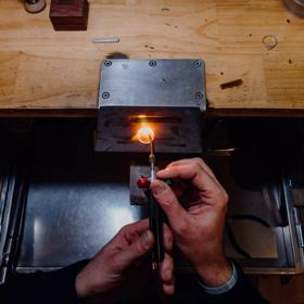Hands brazing a ring together at a wooden bench inside Rawson Brothers Jewellery in Upper Hutt.