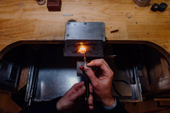 Hands brazing a ring together at a wooden bench inside Rawson Brothers Jewellery in Upper Hutt.