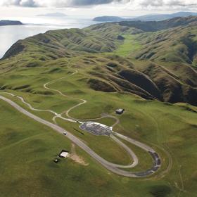 Birds-eye view of racing track at boomrock lodge, with green hills surrounding and kapati coast in the background.