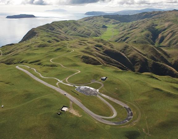 Birds-eye view of racing track at boomrock lodge, with green hills surrounding and kapati coast in the background.