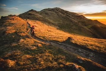 A cyclist wearing a red helmet rides along the Skyline Walkway, a trail in Wellington, New Zealand.