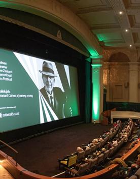 Inside a theatre at Embassy Cinemas, located in Te Aro, Wellington. There are vaulted ceilings, pillars and most of the seats are occupied by audience members. 'Whānau Mārama: New Zealand International Film Festiva' is projected on the large screen.