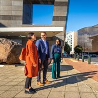 Three people stand outside Te Papa looking across the street.