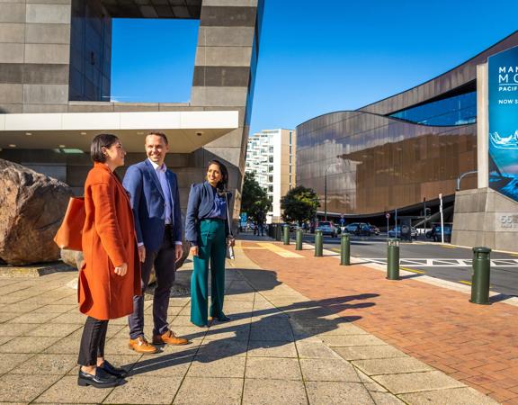 Three people stand outside Te Papa looking across the street.