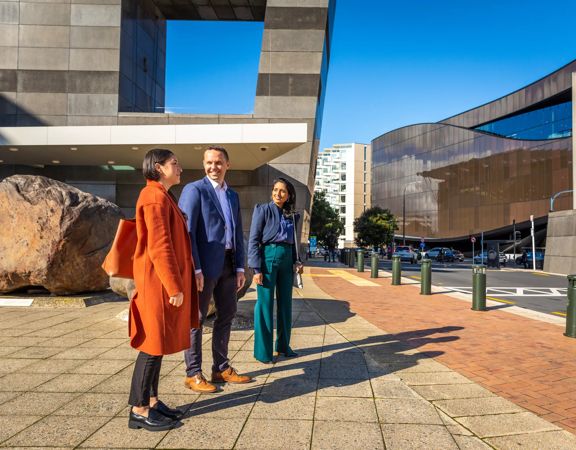 Three people stand outside Te Papa looking across the street.