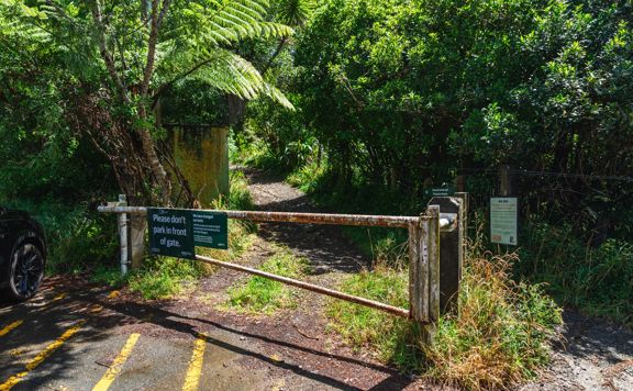 A closed metal gate blocks vehicles from driving onto a walking trail.