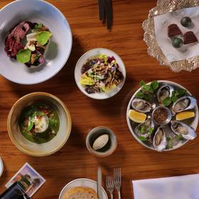 A wooden table with many dishes served at Bellamys restaurant.