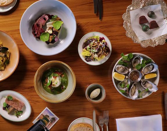 A wooden table with many dishes served at Bellamys restaurant.