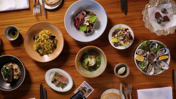 A wooden table with many dishes served at Bellamys restaurant.