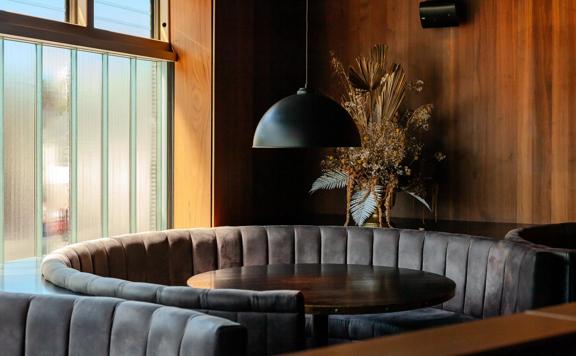The interior of Alma House in Mount Cook. The brown hues of the leather booths and wood walls give an intimate and moody atmosphere.