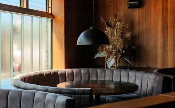 The interior of Alma House in Mount Cook. The brown hues of the leather booths and wood walls give an intimate and moody atmosphere.