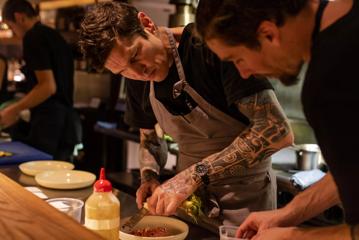 2 chefs serving up plates behind the bar at highwater eatery.