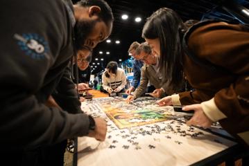 People gather around a table doing a puzzle at APNIC 58 at Tākina.