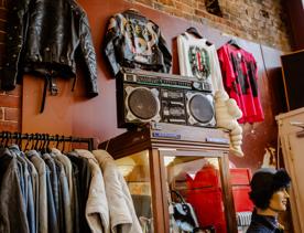 An interior shot of Hunters and Collectors shows leather jackets and t-shirts hanging on the wall, a rack of denim jackets and an old-school boom box sitting on a self.