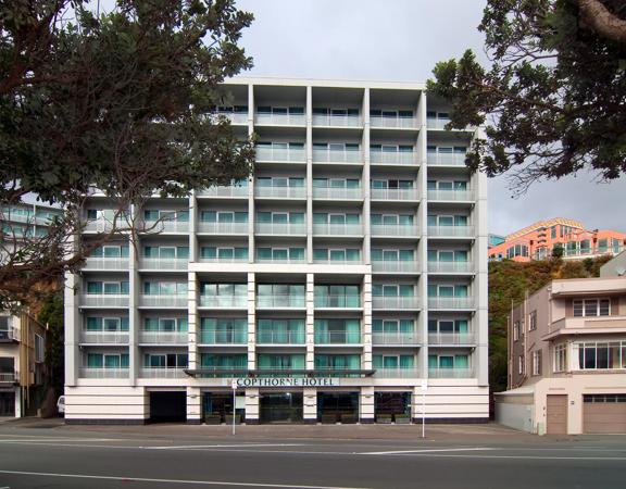 The exterior of Copthorne Hotel, a square shapes building with blue windows, 8 stories tall, and the road in front.