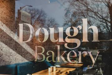 The 'Dough Bakery' sign on the glass window outside Dough Bakery Upper Hutt.
