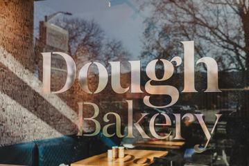 The 'Dough Bakery' sign on the glass window outside Dough Bakery Upper Hutt.