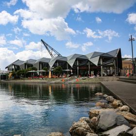 The exterior of Karaka Cafe at Te Wharewaka o Pōneke over the water.