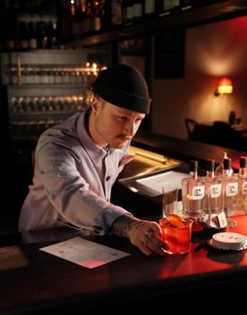 A bartender places a cocktail onto the counter.