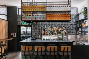 Bar in Atura Hotel with funky patterned wallpaper and bar chairs in foreground.