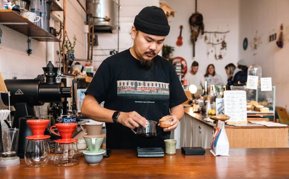 Barista at pour and twist creating their custom coffee on the counter.