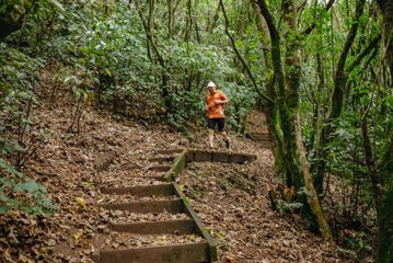 David Haunschmidt doing a trail run in an orange t shirt, surrounded by native forest.