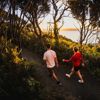 Two people walk along Bus Barn Track in East Harbour Regional Park during golden hour.