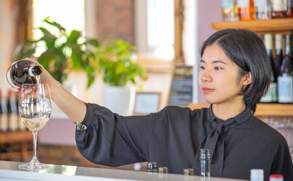 Bar staff from Karahui wine bar pours a glass of white wine.