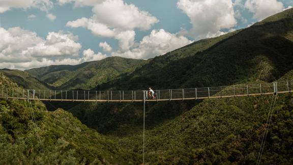 A cyclist is riding on a suspension bridge on the Remutaka Cycle trail in Upper Hutt.