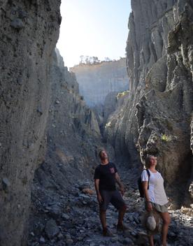 Two people stand in a rocky canyon at the Putangirua Pinnacles track in the Wairarapa.