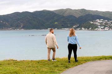 Two people walk along the grassy shoreline at Whitireia Park in Porirua.