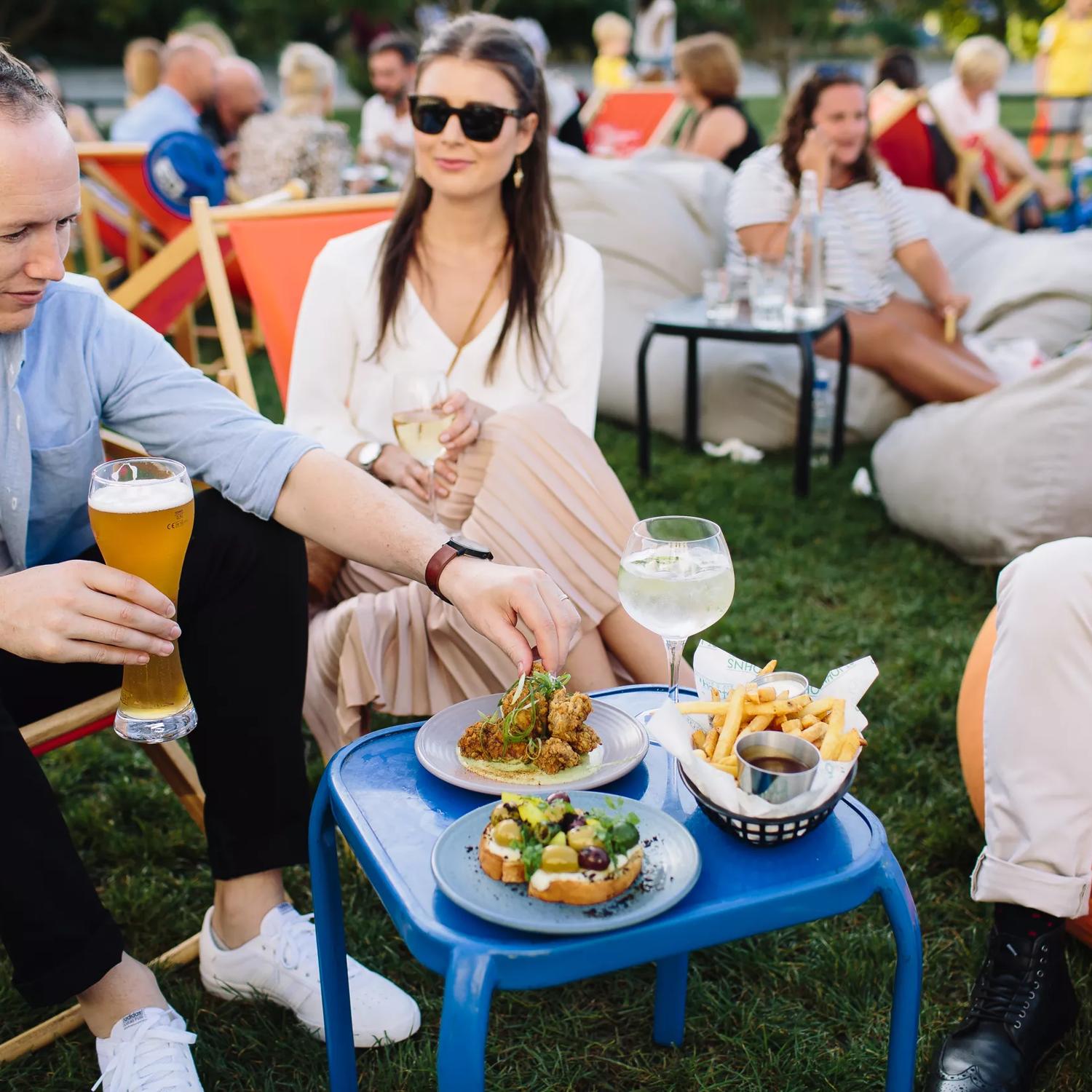 A group of friends enjoy drinks and appetizers on the lawn at St. Johns Bar & Eatery.