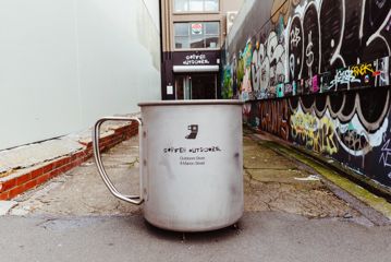 An oversized replica enamel mug that doubles as a sign for the Coffee Outdoors Wellington store at 8 Marion Street.